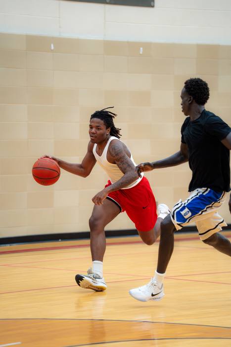 Player in red shorts driving past a defender